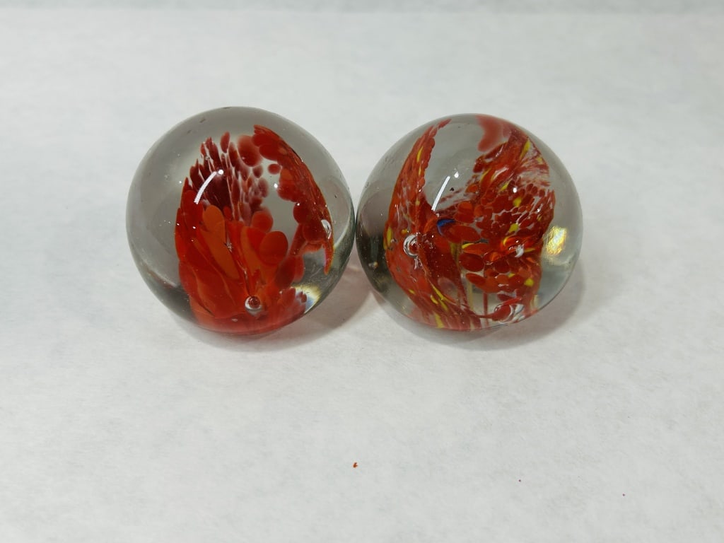 Hand-Blown Art Glass Paperweights in the Murano Style: This pair of hand-blown art glass spheres is executed in the Murano style, featuring internal plume-like decorations in a vibrant red color. These structures, often referred to as octopus motifs, are 