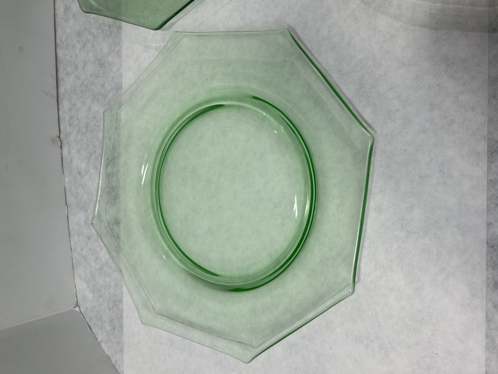 Uranium Green Depression Glass Salad Plates: This collection consists of three pieces of transparent light green uranium glass, which exhibits a strong neon-green fluorescence under ultraviolet (UV) light. The group includes two octagonal plates
