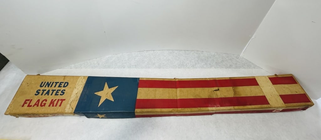 Vintage United States Flag Kit in Original Box: A vintage United States flag kit presented in its original elongated cardboard box. The box features printed graphics depicting a blue canton with a single star and red and white stripes, labeled UNIT