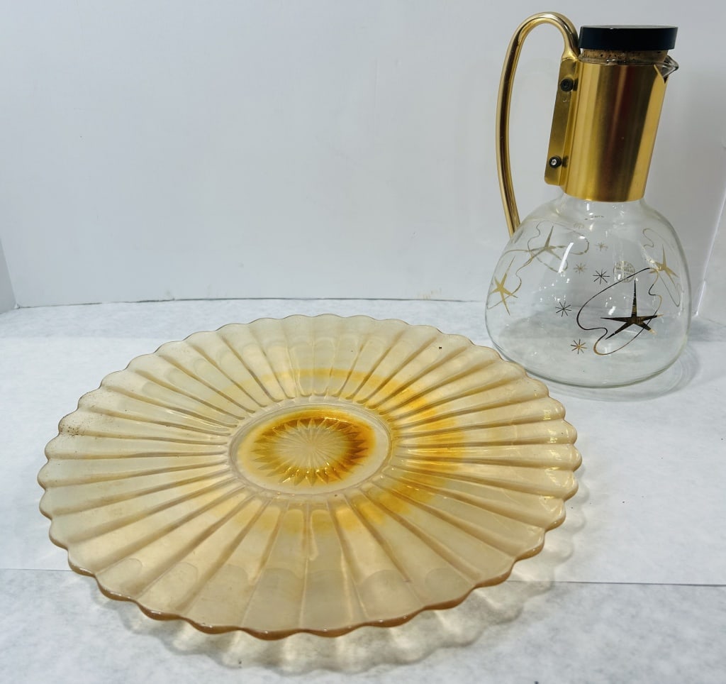 Mid-Century Modern Glass Tableware Including a Pyrex for Wesco Carafe: A group of two pieces of Mid-Century Modern glassware. The first item is a clear glass carafe decorated with gold-toned atomic starbursts and stylized line motifs. It is fitted with a gold-toned metal