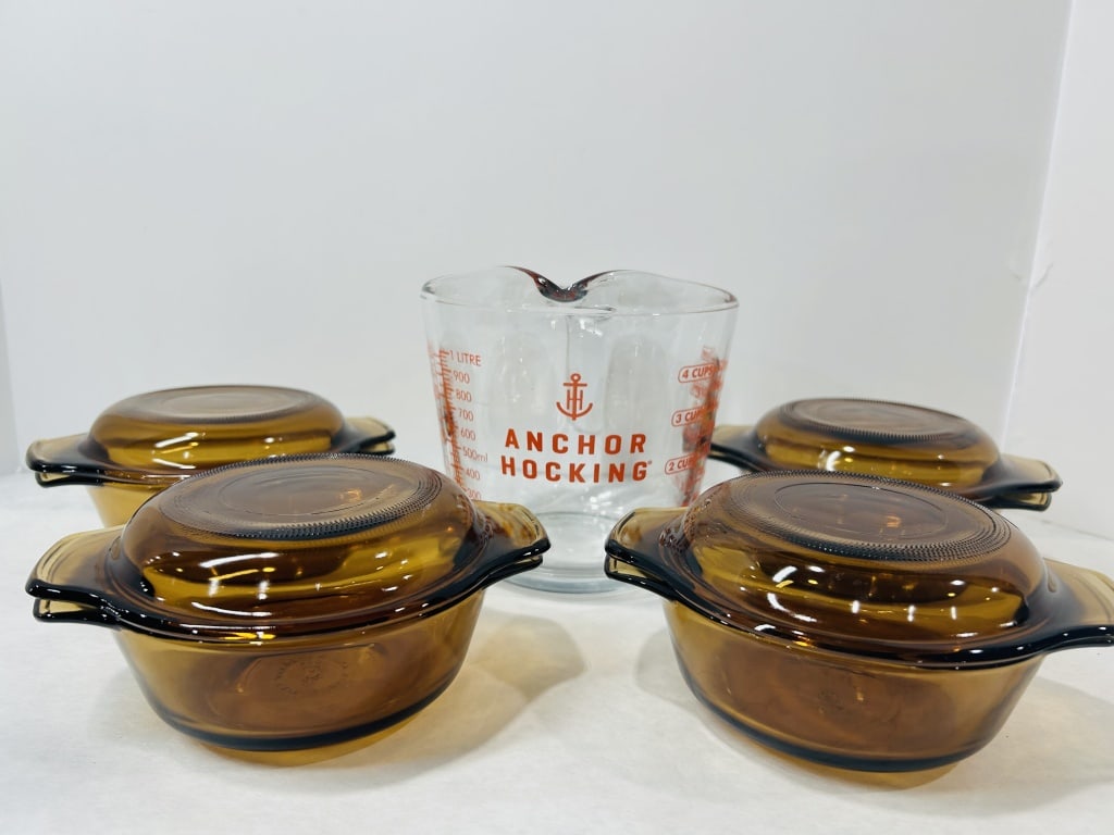 A Collection of Anchor Hocking Amber Glass Kitchenware: A collection of Anchor Hocking kitchen glassware comprising several individual amber-tinted lidded casserole dishes and a clear glass measuring pitcher. The amber-colored dishes are designed with inte