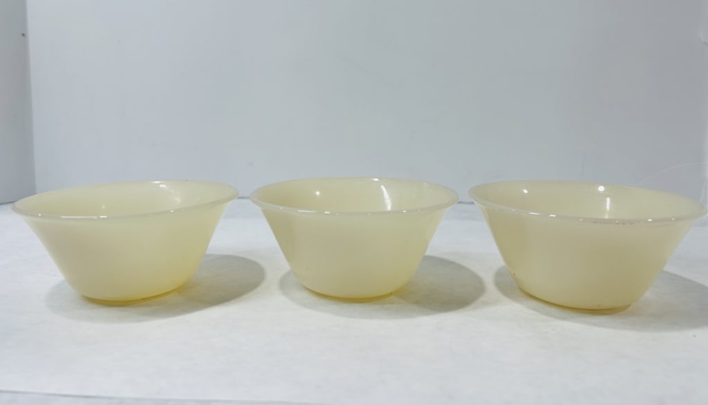 A Trio of Fire-King Ivory Glass Custard Bowls: A trio of Fire-King ivory glass custard bowls. These mid-century utilitarian pieces are constructed from heat-resistant translucent glass. Each bowl features a tapered conical body ending in a slightl