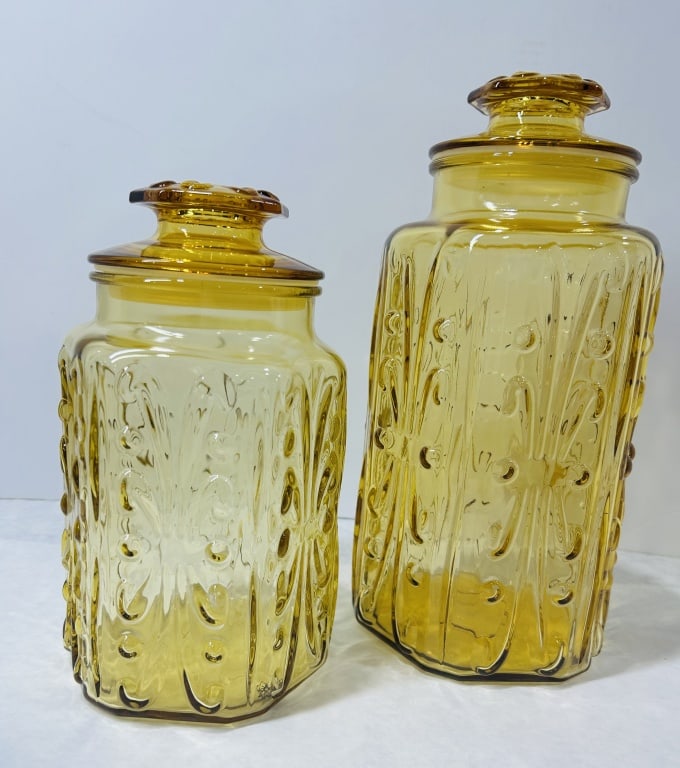 Pair of Mid-Century Amber Glass Canisters L.E. Smith: This lot consists of a pair of mid-century modern amber-colored pressed glass canisters with coordinating lids. Each vessel features a prominent embossed pattern of vertical stylized teardrops accente