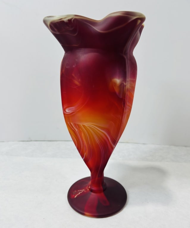 A Mid-20th Century Swirled Slag Glass Ruffled Footed Vase: This footed art glass vase features a wide ruffled rim and a tapering body mounted on a circular pedestal foot. The piece is crafted from swirled slag glass with a marbled pattern of deep red, orange,