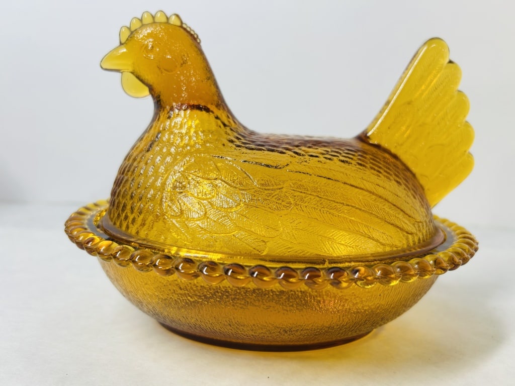 Amber Glass Hen on Nest Covered Dish Indiana Glass Company: An amber pressed glass Hen on Nest covered dish attributed to the Indiana Glass Company. This two-piece set consists of a lid molded in the shape of a nesting hen and a matching oval base. The hen lid