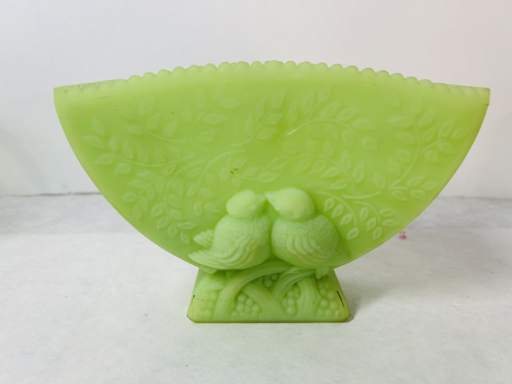 Fenton Lime Green Satin Custard Glass Lovebirds Fan Vase: This is a fan-shaped pedestal vase produced by the Fenton Art Glass Company. The item is crafted from lime green custard glass with a satin finish. This specific glass type contains uranium, which cau