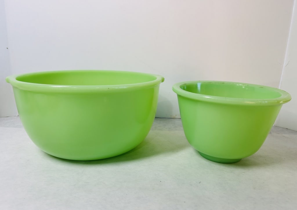Two Uranium Jadeite Glass Mixing Bowls: Two mixing bowls of varying sizes, fashioned from opaque, milky green jadeite-style glass. The composition includes uranium, as evidenced by the strong neon green fluorescence displayed under ultravio
