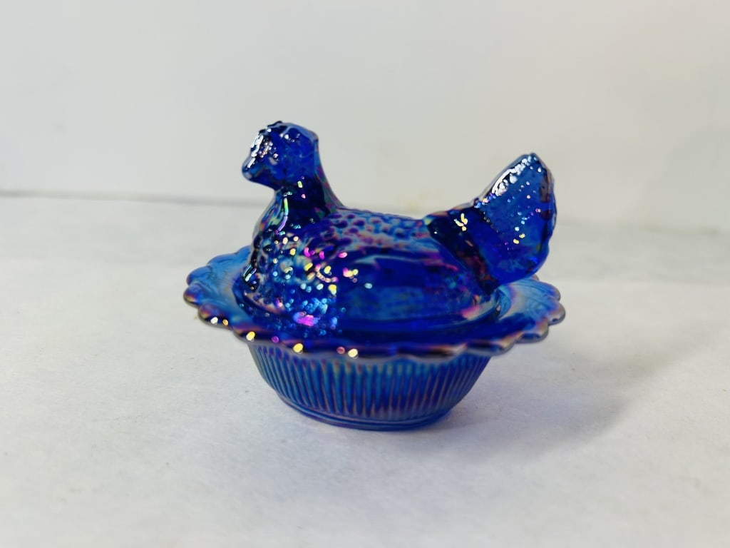 Mosser Cobalt Blue Carnival Glass Miniature Hen on Nest: A miniature two-piece covered glass dish featuring the Hen on Nest motif, manufactured by Mosser Glass. The piece is made of molded cobalt blue glass finished with a vibrant iridescent carnival coatin
