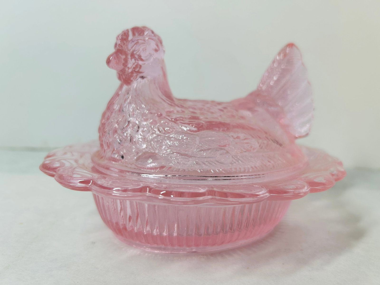 Mosser Pink Carnival Glass Miniature Hen on Nest: A miniature two-piece covered glass dish featuring the Hen on Nest motif, manufactured by Mosser Glass. The base features a vertical ribbed design on the exterior and a wide, flared rim with a scallop
