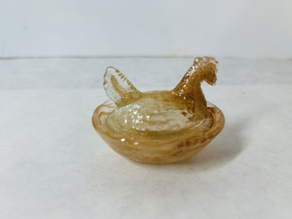 Slag Glass Miniature Hen on Nest Covered Dish: This two-piece miniature covered dish is designed in the form of a hen on a nest, a style often utilized as a salt cellar or decorative trinket dish. The piece is constructed from pressed slag glass, 
