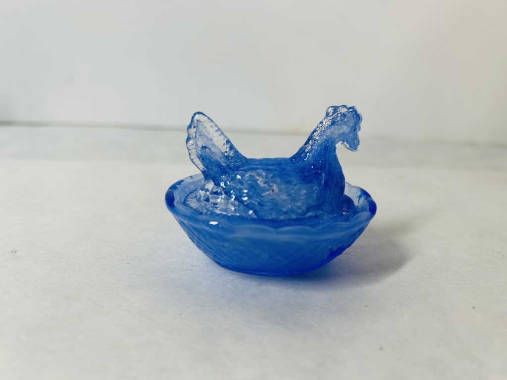 Miniature Blue Swirl Slag Glass Hen on Nest Salt Cellar: This miniature two-piece covered dish is designed as a hen on a nest, a form traditionally used as a salt cellar. The item is made of pressed slag-style glass, featuring a translucent blue body with d