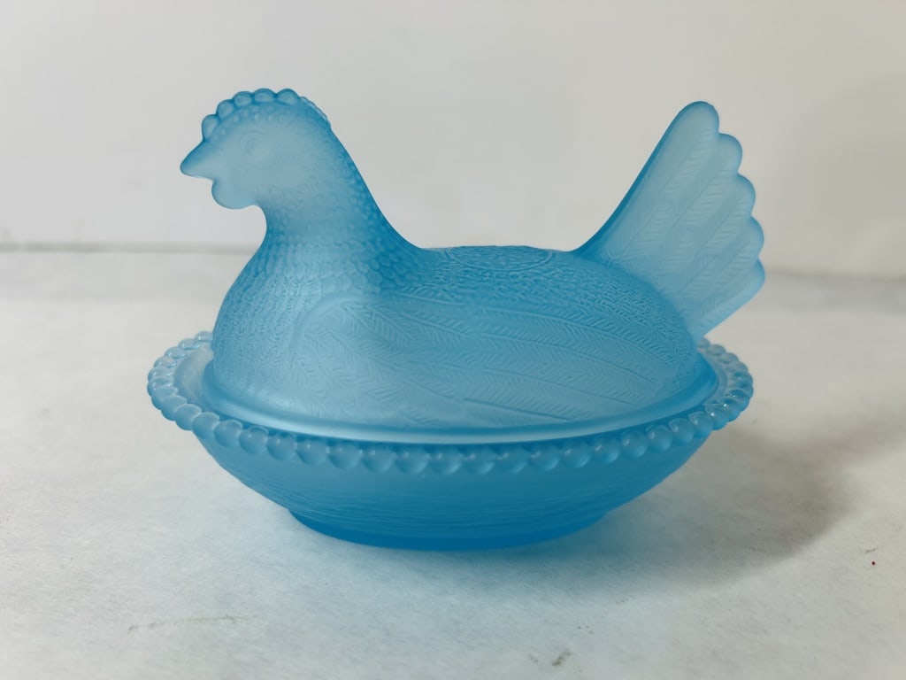 Turquoise Satin Glass Hen on Nest Covered Dish: This two-piece covered candy or trinket dish is crafted in the traditional form of a nesting hen. The piece is made of turquoise blue satin glass, characterized by a frosted, matte exterior and a glos