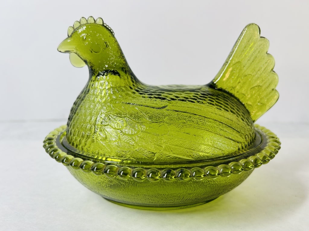 Vintage Green Pressed Glass Hen on a Nest Covered Dish Indiana Glass Company: A vintage two-piece covered candy dish crafted in translucent lime green pressed glass. The design features a lid modeled in the form of a sitting hen with detailed plumage, a prominent comb, and a wa