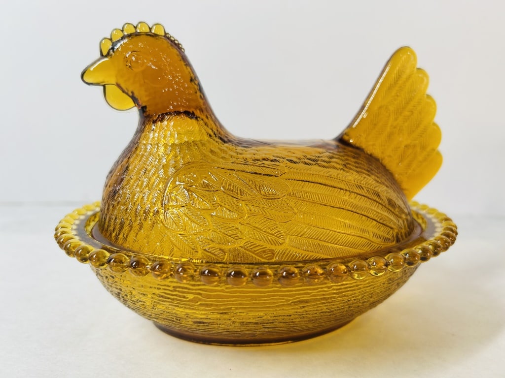 Amber Glass Hen on Nest Covered Dish Indiana Glass: A two-piece pressed glass covered novelty dish in honey amber, featuring the Hen on Nest motif, attributed to the Indiana Glass Company. The lid is molded in the form of a nesting chicken with detaile