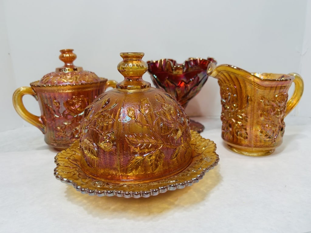 A Collection of American Carnival Glass Including Imperial Lustre Rose Pattern Items: This group consists of several pieces of American pressed glass with an iridescent carnival finish. Pieces in a marigold color feature the Lustre Rose pattern, attributed to the Imperial Glass Company