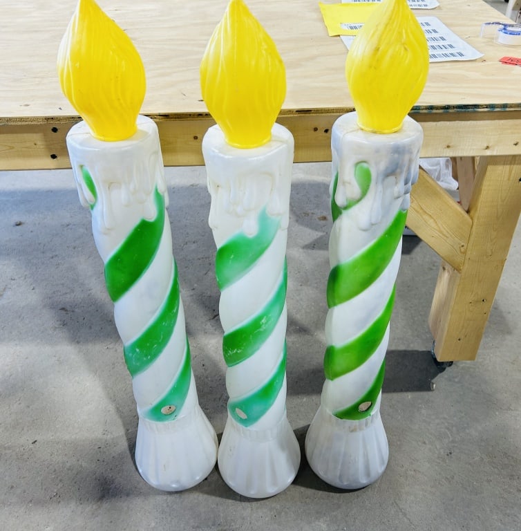 Three Vintage Blow Mold Striped Christmas Candle Decorations: A trio of large-scale holiday blow mold decorations in the form of candles. Each unit is constructed from molded plastic, featuring a white body decorated with a diagonal green spiral stripe. The uppe