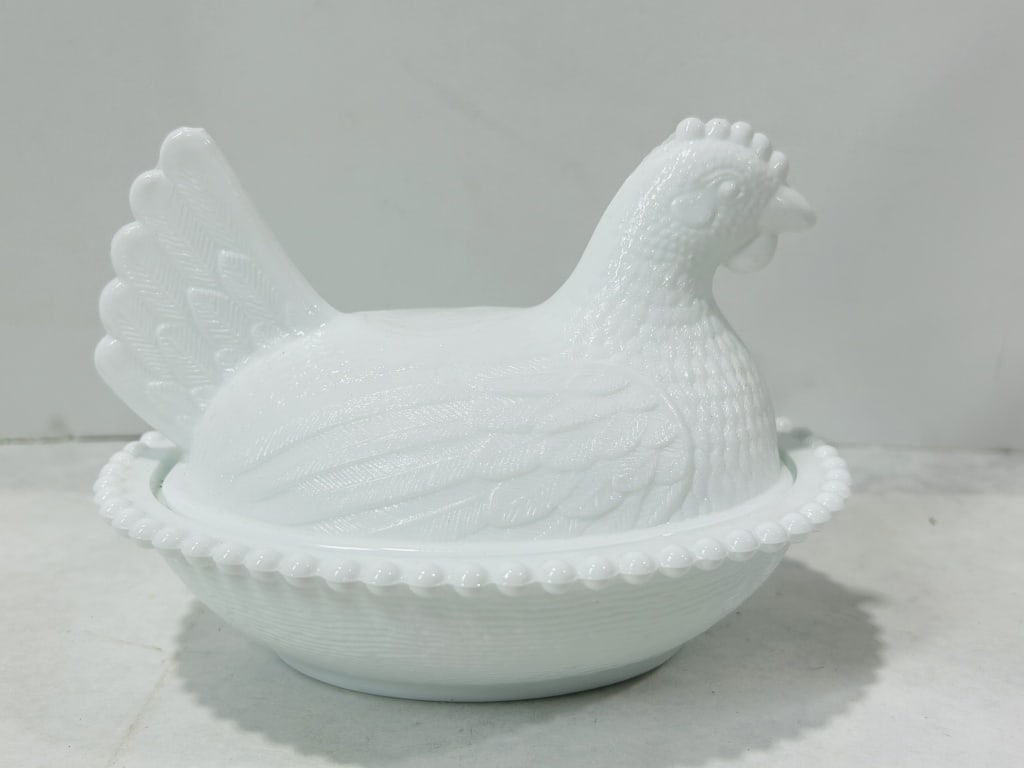 Vintage White Milk Glass Hen on Nest Covered Dish, Attributed to Indiana Glass Company: A two-piece covered animal dish crafted from opaque white milk glass. The lid is molded in the form of a nesting hen, featuring textured feathering across the body and wings, a multi-tiered tail, and 