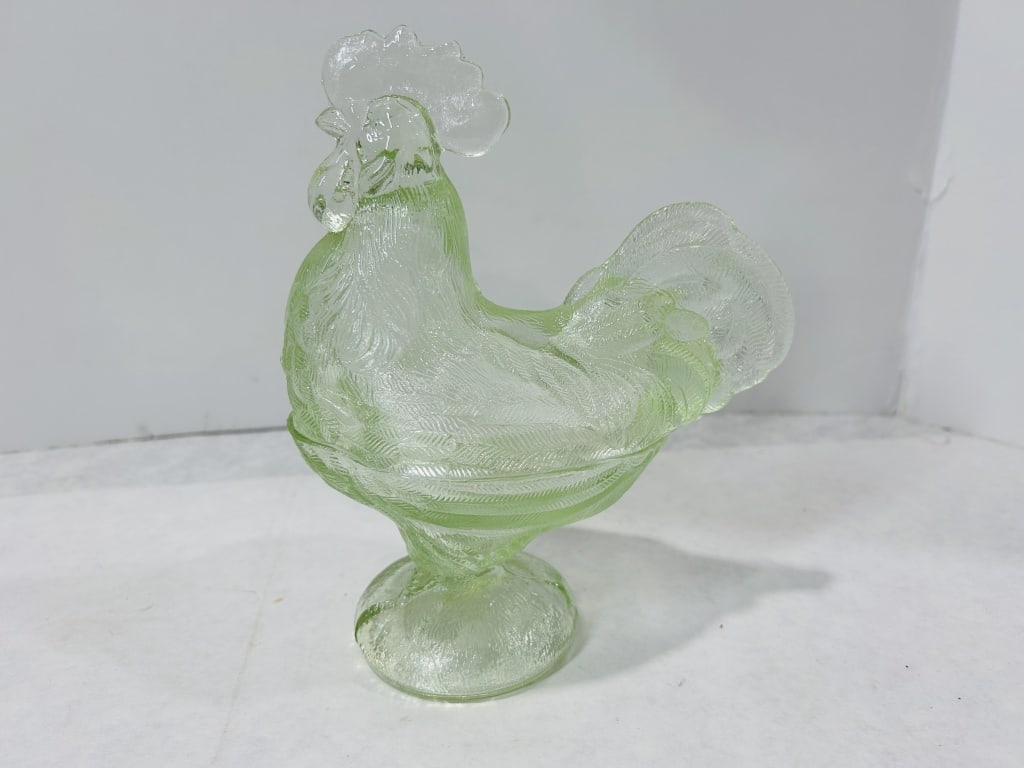 A 20th-Century Pressed Light Green Glass Rooster Covered Pedestal Candy Dish: A two-piece covered candy dish crafted from translucent light green pressed glass in the form of a standing rooster. The dish features a lid comprising the upper body and head of the bird, which fits 