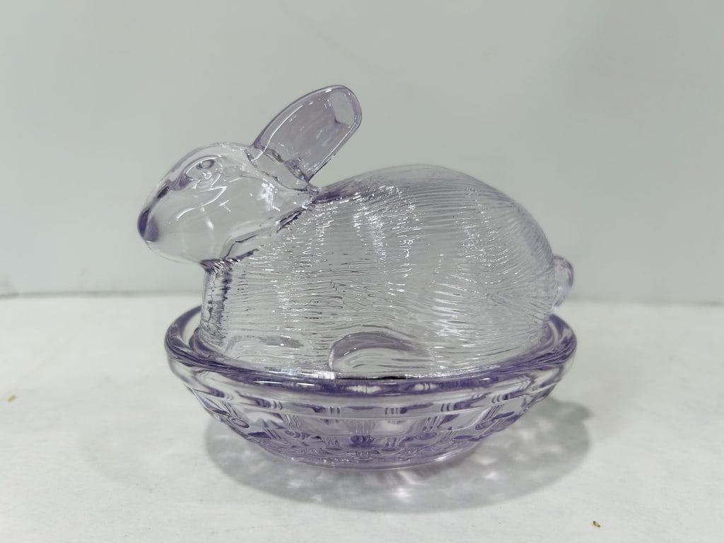 Pale Lavender Pressed Glass Rabbit on Nest Covered Dish: A two-piece pressed glass covered dish in a pale lavender hue, commonly identified as a Rabbit on Nest or Bunny on Basket dish. This item is in the style of 20th-century American glass production by m