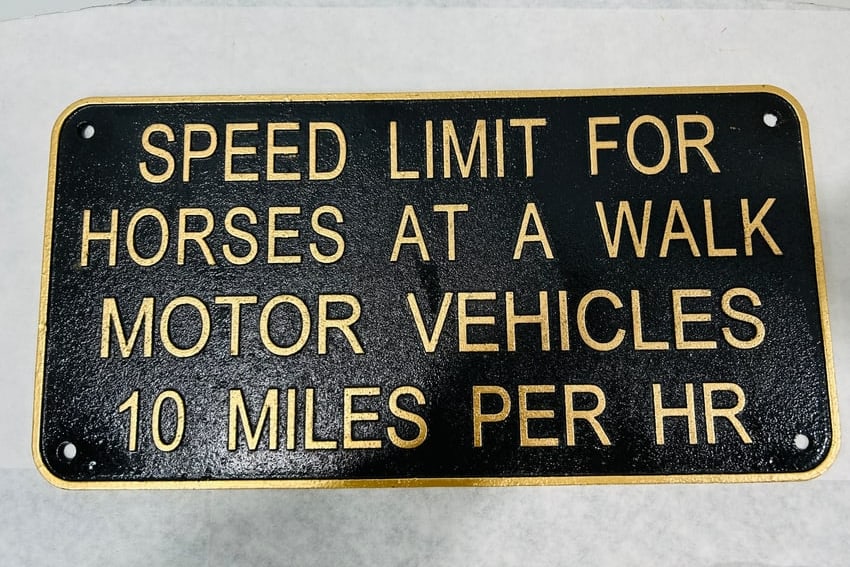 Cast Iron Speed Limit for Horses and Motor Vehicles Sign Plaque: This item is a cast metal sign, likely cast iron, featuring a textured sand-cast finish. The sign is rectangular with rounded corners and includes four pre-drilled mounting holes, one at each corner. 