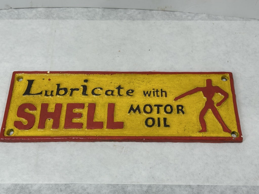 Shell Motor Oil Advertising Sign with Lubricating Man Mascot: A rectangular advertising sign for Shell Motor Oil featuring embossed graphics and text. The sign is constructed from cast iron with a painted finish, exhibiting a textured surface characteristic of s