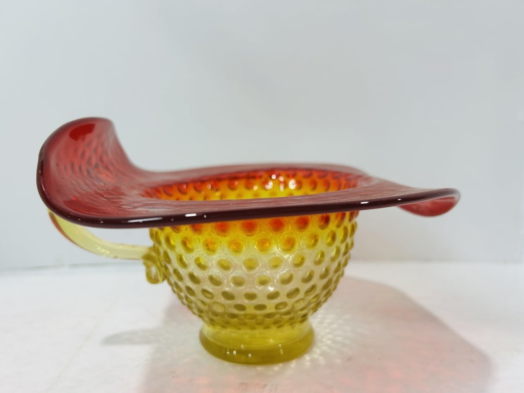 Vintage Amberina Hobnail Glass Top Hat Whimsy with Single Handle: This vintage art glass decorative piece is fashioned in the form of a top hat, a style often referred to as a whimsey or posy vase. The item is characterized by a vibrant amberina color gradient, tran