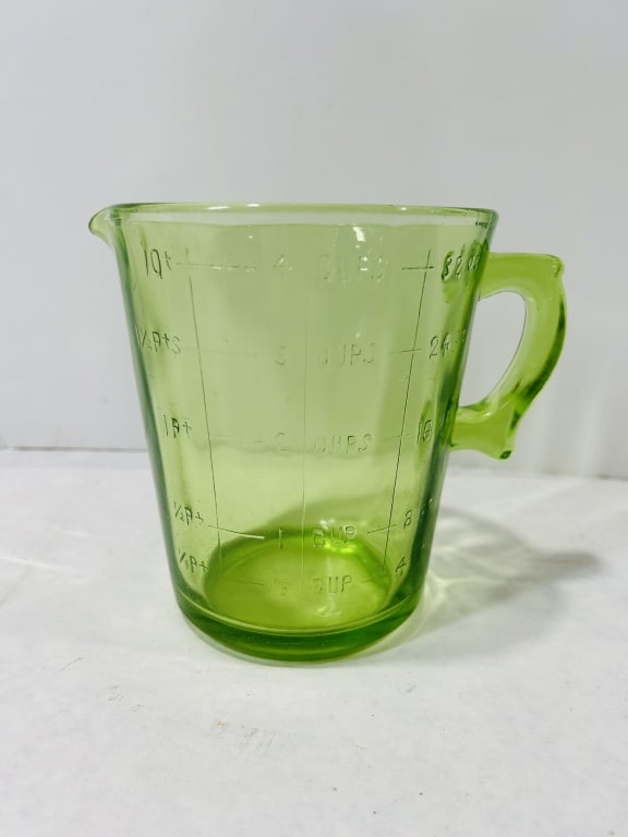Large Uranium Green Depression Glass One Quart Measuring Cup: A large liquid measuring cup from the Depression era with a one-quart capacity, manufactured from transparent green glass. The material is confirmed as uranium glass, exhibiting a strong neon-green fl