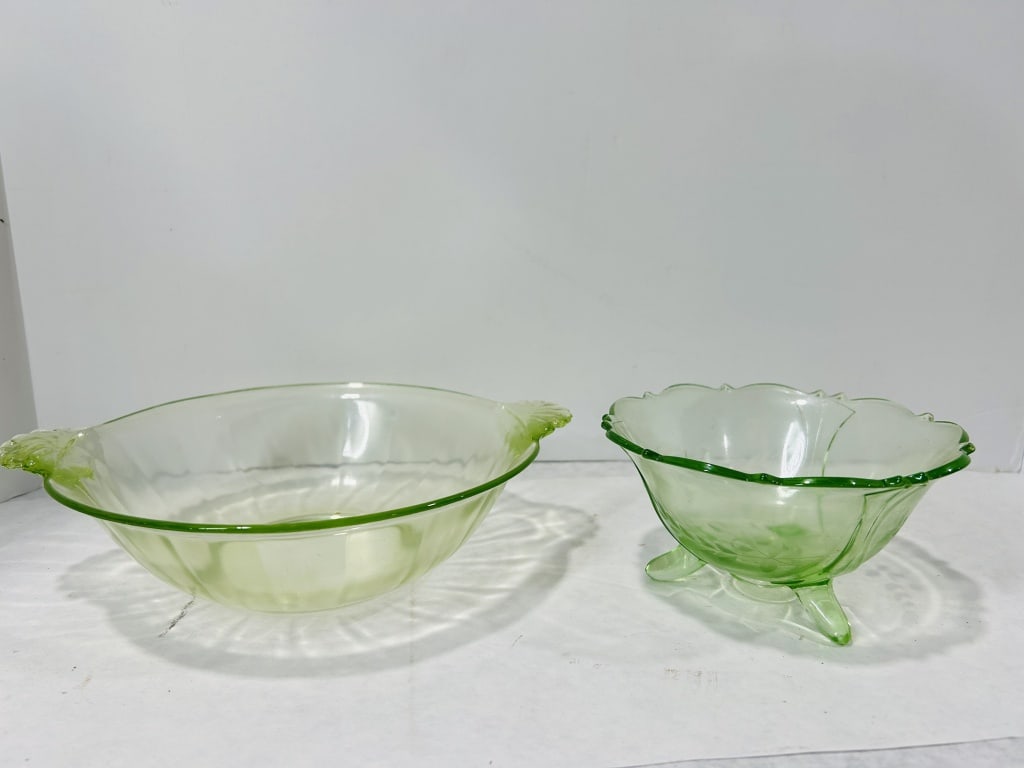 A Pair of Green Depression Uranium Glass Serving Bowls: This pair of transparent pale green glass items consists of two distinct Depression-era pieces that exhibit a strong, brilliant neon green fluorescence under ultraviolet light, confirming their compos