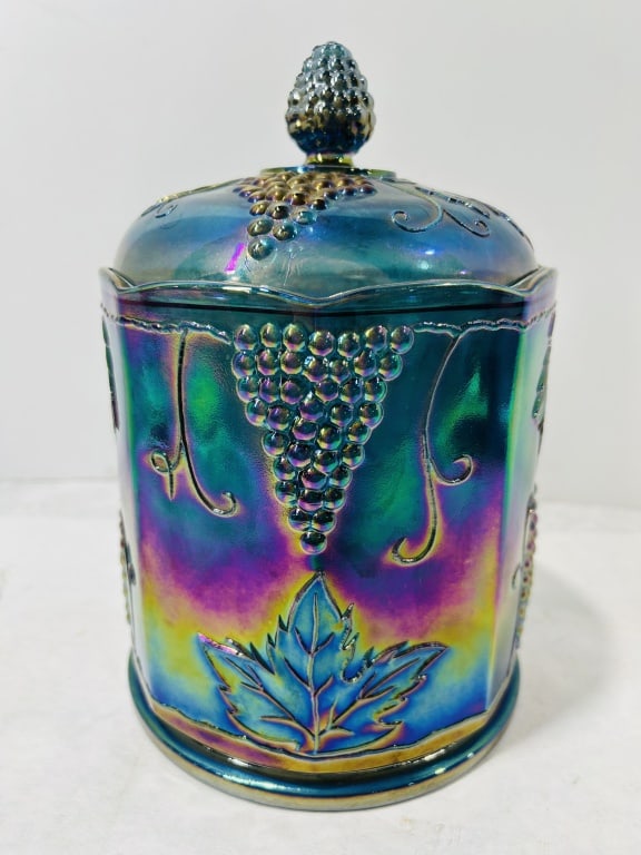 Vintage Harvest Grape Iridescent Blue Carnival Glass Lidded Canister: This is a lidded canister or tobacco jar made of iridescent blue carnival glass in the Harvest Grape pattern, attributed to the Indiana Glass Company. The piece is crafted from pressed cobalt blue gla
