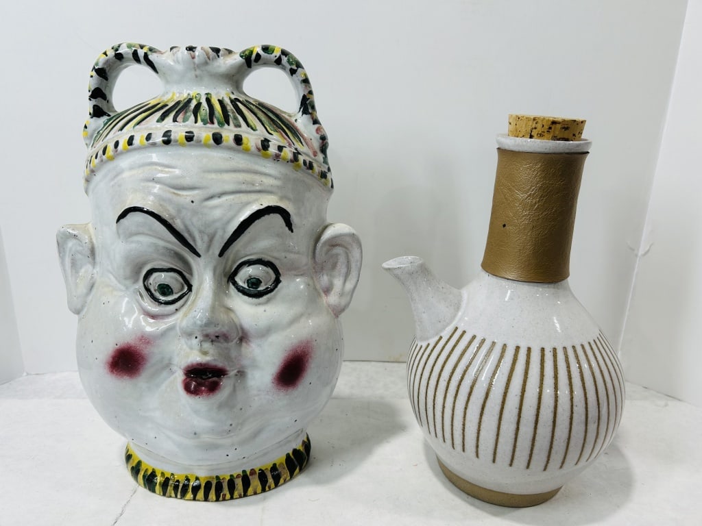 Two Decorative Ceramic Pitchers including a Fratantoni Sicilian Maiolica Character Jug: This lot features two ceramic pitchers of contrasting design styles. The first item is a Sicilian maiolica character jug in the form of an anthropomorphic face with twin loop handles at the rim. It is