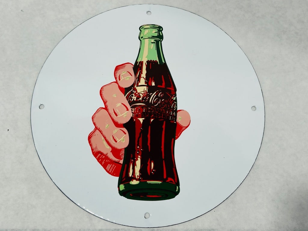 Coca-Cola Round Porcelain Enamel Advertising Sign by Rhyne and Son: This is a circular porcelain enamel advertising sign for Coca-Cola, featuring a pop-art style graphic of a hand grasping a classic green glass contour bottle. The sign is constructed from heavy-gauge 