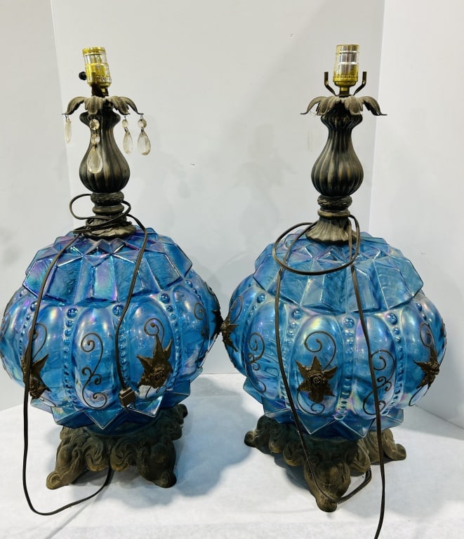Pair of Hollywood Regency Iridescent Blue Carnival Glass Table Lamps in the Style of Carl: A pair of large Hollywood Regency style table lamps featuring iridescent blue carnival glass bodies. Each lamp consists of a blown-molded glass globe with a faceted, geometric upper section and a lobe