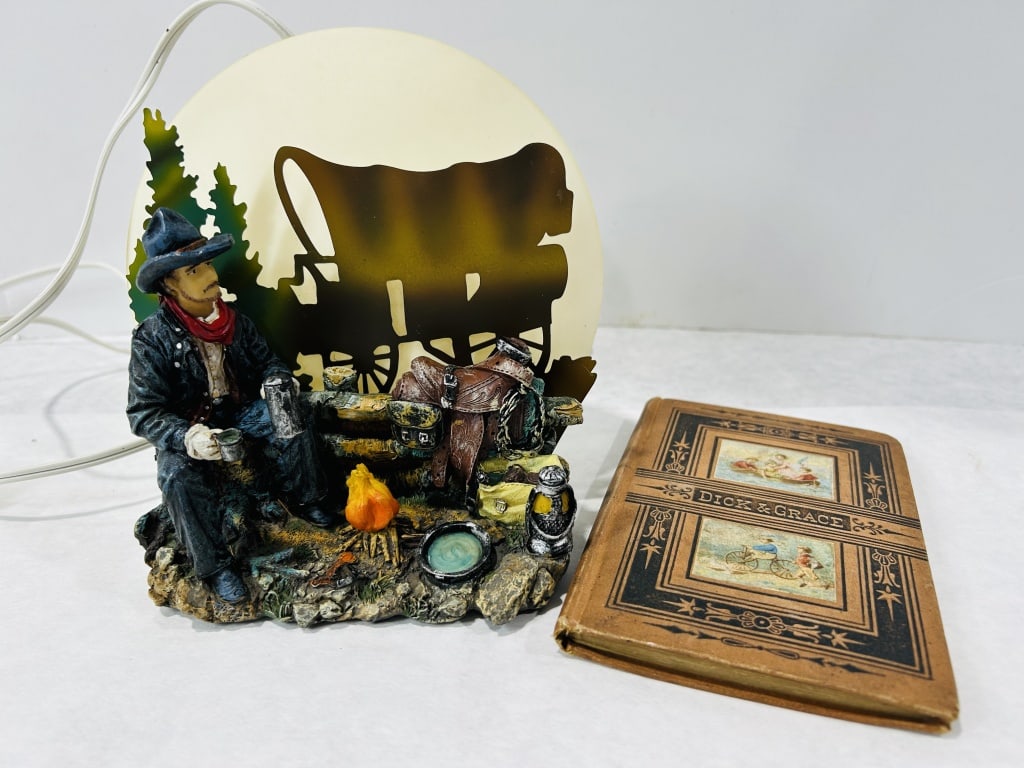 Two Western-Themed Items including a Novelty Night Light and an Antique Children's Book: This lot features two items with Western and vintage themes: a decorative novelty table lamp and a late 19th-century children's book. The lamp depicts a hand-painted campfire scene with a seated cowbo
