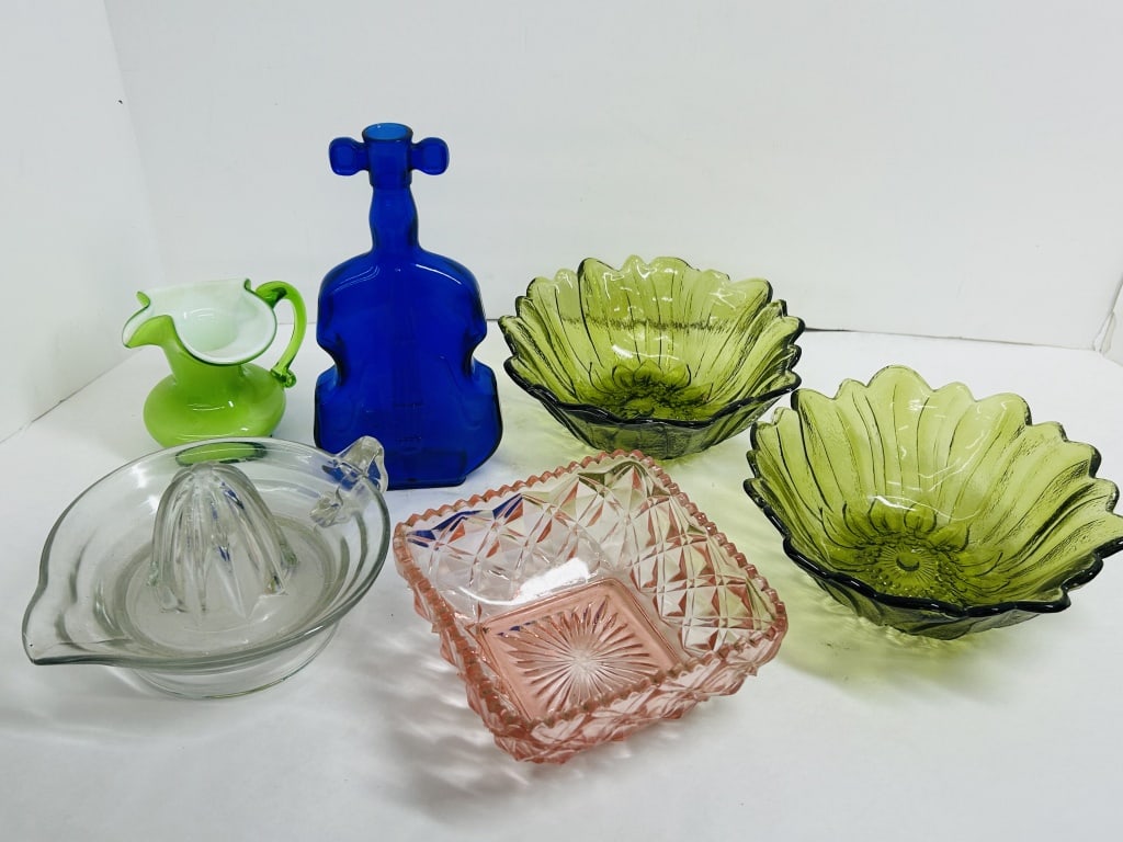 VARIOUS MAKERS, ASSORTED GLASSWARE, 20TH CENTURY: A collection of mid-20th-century glassware including sunflower-patterned green bowls, a cobalt blue violin-form bottle, and a cased green glass pitcher. The group also features a pink pressed glass bo