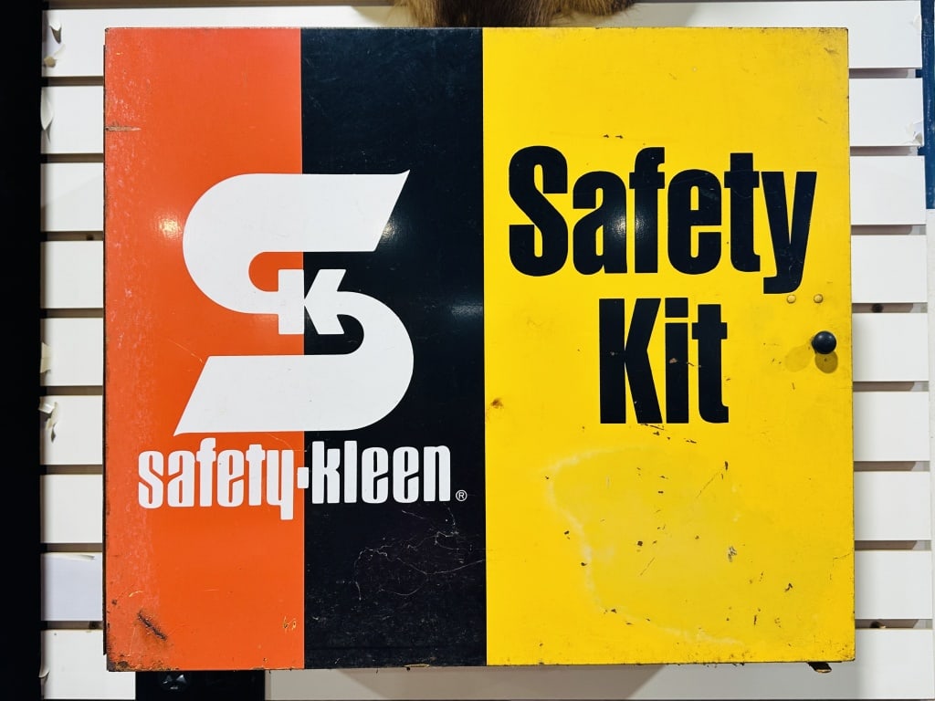 SAFETY-KLEEN METAL INDUSTRIAL SAFETY KIT: Industrial wall-mounted metal cabinet featuring Safety-Kleen tri-color branding and stylized logo. The interior includes two shelves containing a 3M respirator and absorbent hydrocarbon pads.