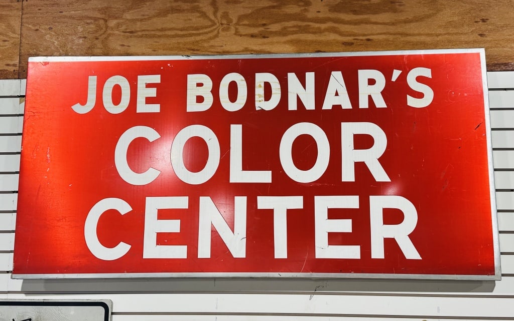 JOE BODNAR PAINTED METAL SIGN: A vintage rectangular painted metal advertising sign for Joe Bodnar's Color Center, featuring white sans-serif block lettering against a red ground. The sign is encased in a minimalist silver-toned me