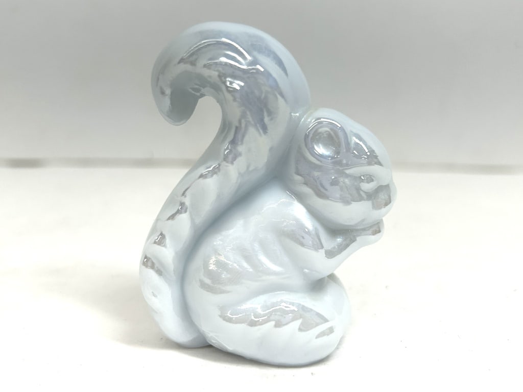 WHITE IRIDESCENT BOYD SQUIRREL: Iridescent pressed glass figurine attributed to Boyd's Crystal Art Glass as the 'Sammy the Squirrel' model, featuring a seated pose and pearlescent glaze. Faint, illegible markings are present on the