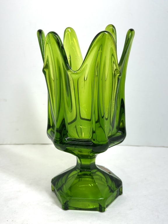 VIKING GREEN GLASS SWUNG VASE, CIRCA 1960: Mid-century modern translucent green glass swung vase by Viking Glass Company featuring a flared six-pointed rim with vertical ribbing. The vessel is supported by a faceted hexagonal pedestal foot
