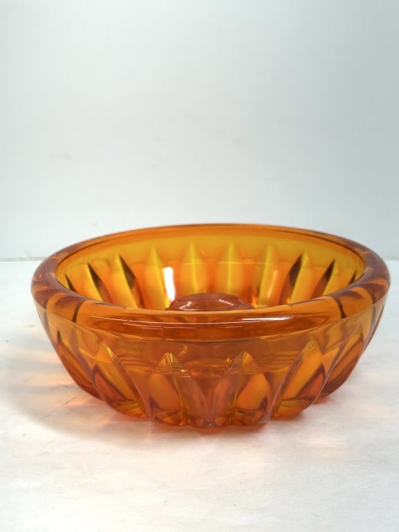 VINTAGE ORANGE GLASS BOWL, 1960S: A heavy-walled orange glass vessel featuring a molded sunburst pattern and a smooth, rounded rim. The interior is characterized by a raised central medallion with three parallel ridges.