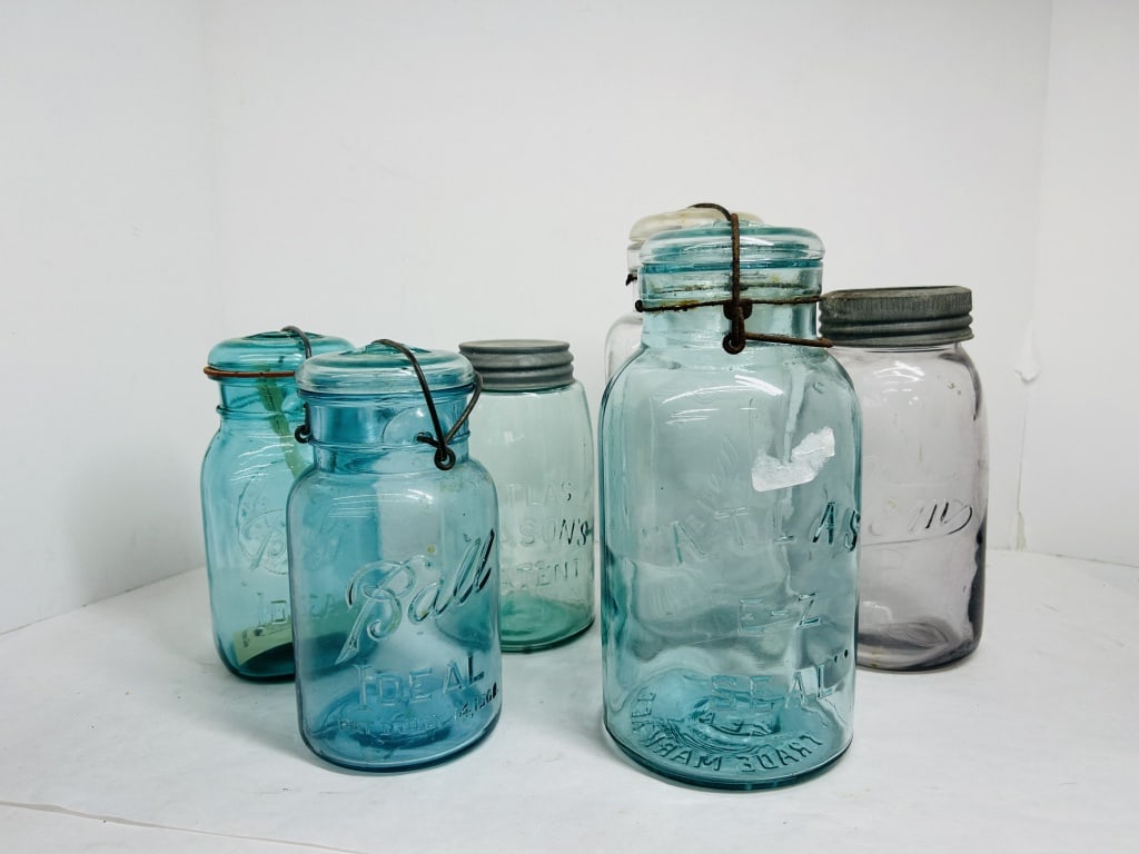 SIX VARIOUS GLASS CANNING JARS, 20TH CENTURY: An assortment of six machine-made glass canning jars featuring embossed markings from Ball, Atlas, Kivlan Smalley, and Wallaceburg. The group includes various closures such as glass lids with wire bai