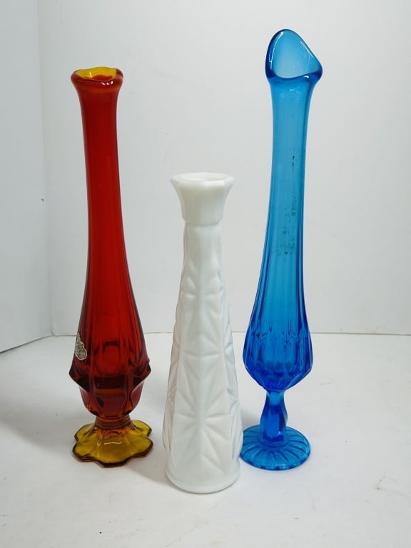 FENTON AND VINTAGE GLASS VASES, 1990S: A trio of decorative glass vases, including a Fenton Amberina swung vase, a milk glass bud vase with geometric motifs, and a blue ribbed swung vase. An embossed Fenton mark with the number nine is vis