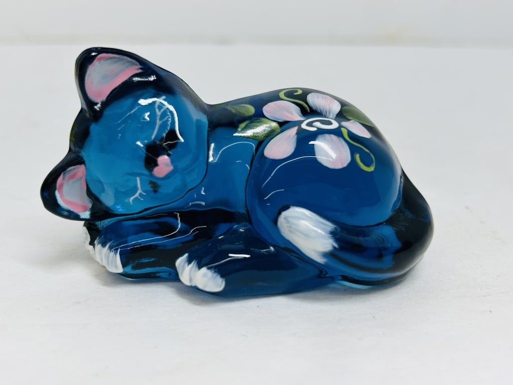FENTON COBALT GLASS SLEEPING CAT, C. 1995: Hand-painted cobalt blue art glass figurine produced by Fenton Art Glass Company in the form of a sleeping cat. The base features the hand-painted signature of artist Diane Van Zile.Length: 3 inches.
