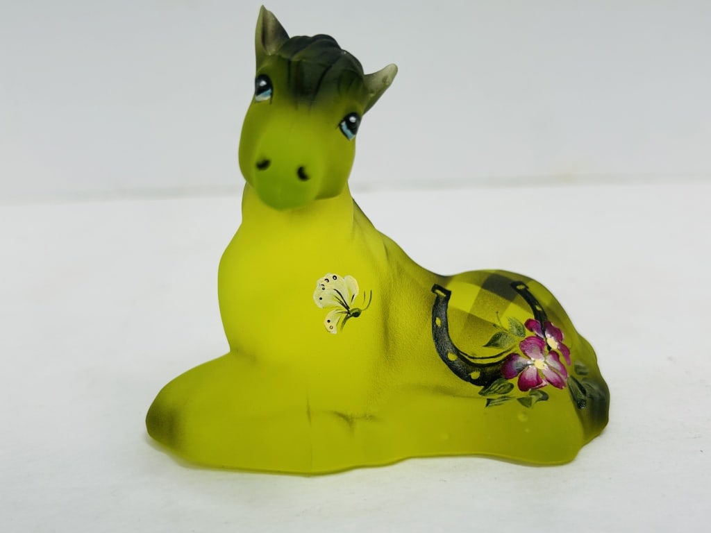 FENTON PAINTED URANIUM GLASS PONY, 2025: Reclining pony figurine produced from the Fenton Art Glass Company mold and hand-painted by artist Michelle Kibbe. The frosted uranium glass glows under ultraviolet light and features hand-painted flo