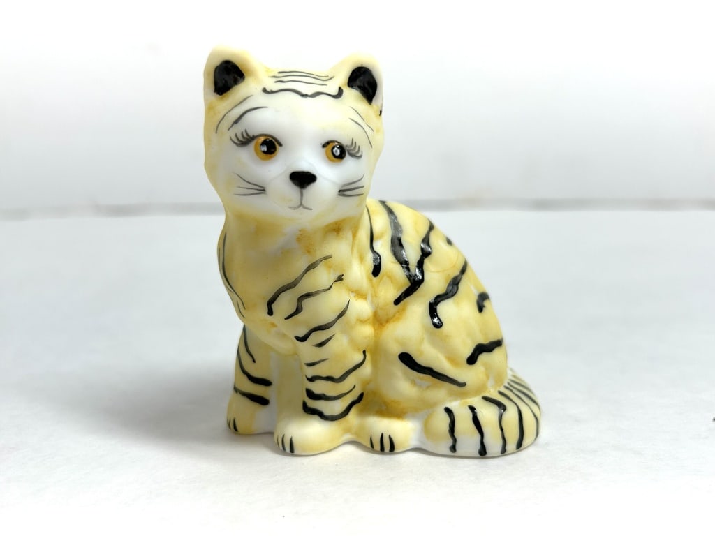 FENTON HP TIGER, VINTAGE: A hand-painted glazed ceramic miniature depicting a seated tiger cub with expressive orange eyes and distinctive black stripes. The figurine bears a handwritten mark for Shell on the lower back near t