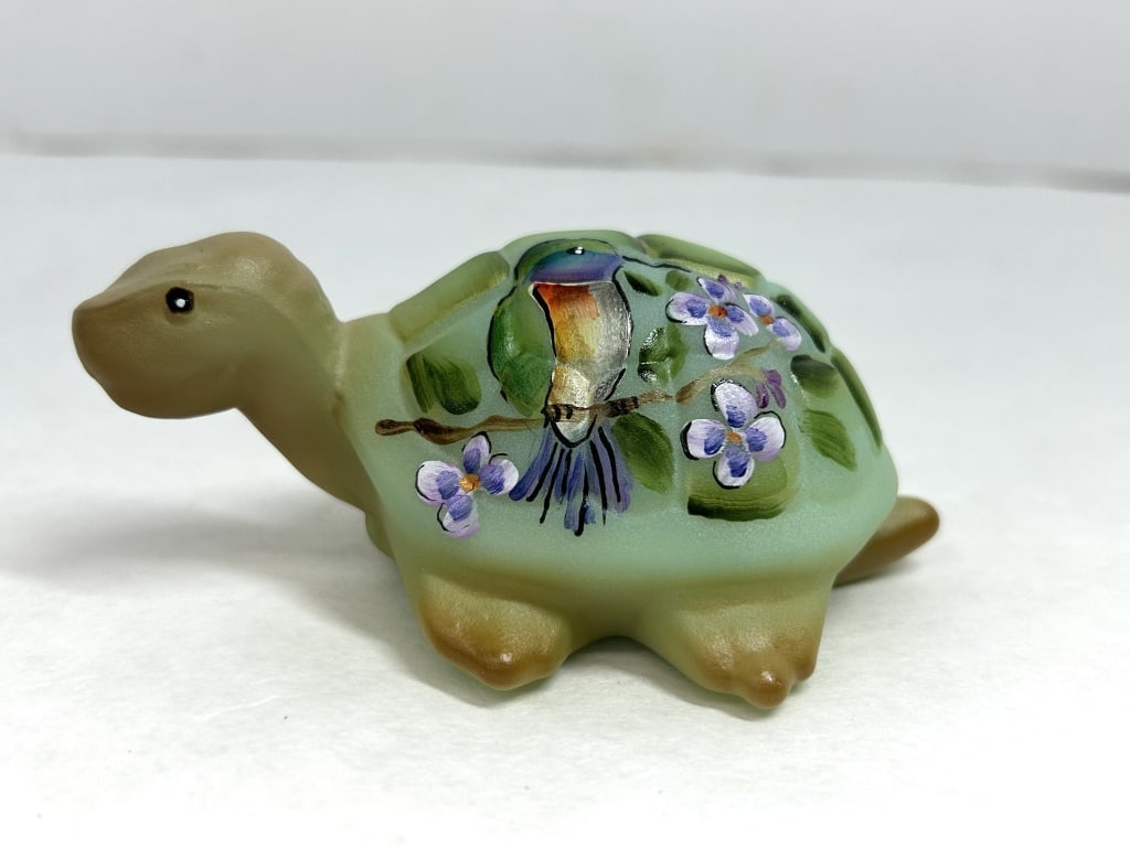 FENTON PAINTED GLASS TURTLE, 2024: Contemporary satin glass turtle figurine produced from a Fenton Art Glass mold, featuring a hand-painted scene of a songbird perched on a flowering branch. The underside is hand-signed by artist Kim B