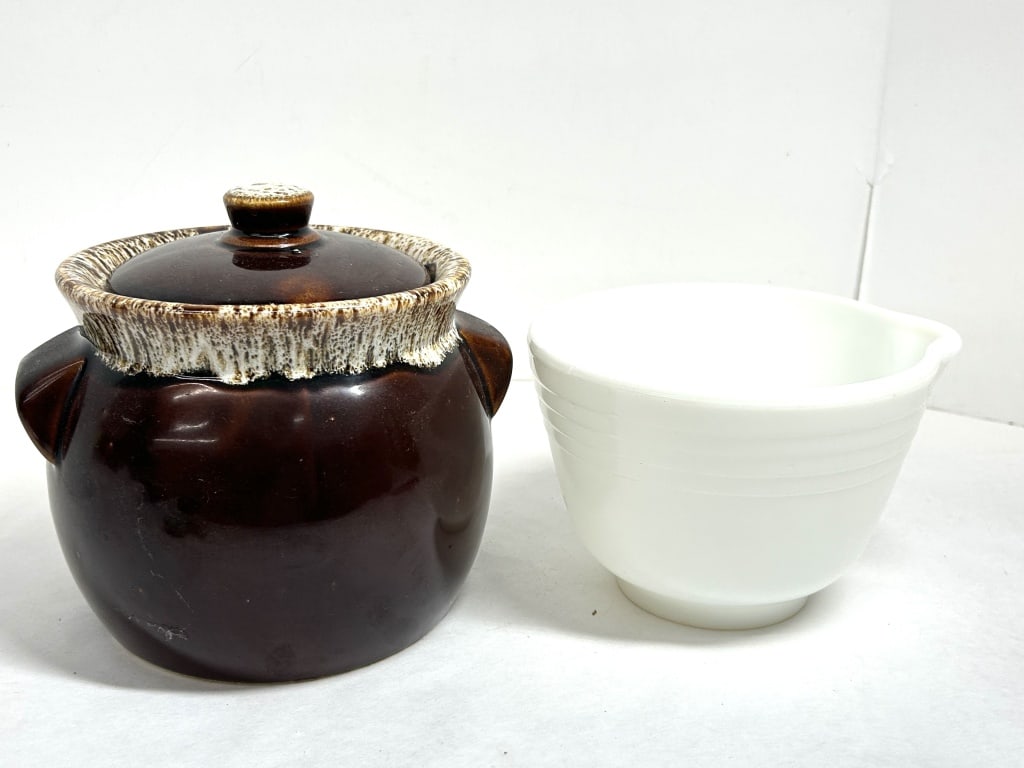 HULL STYLE AND PYREX KITCHENWARE, 1950: A two-piece lot featuring a brown drip-glazed ceramic bean pot in the style of Hull Pottery and a Pyrex milk glass mixing bowl. The bowl displays an embossed mark on the underside indicating productio