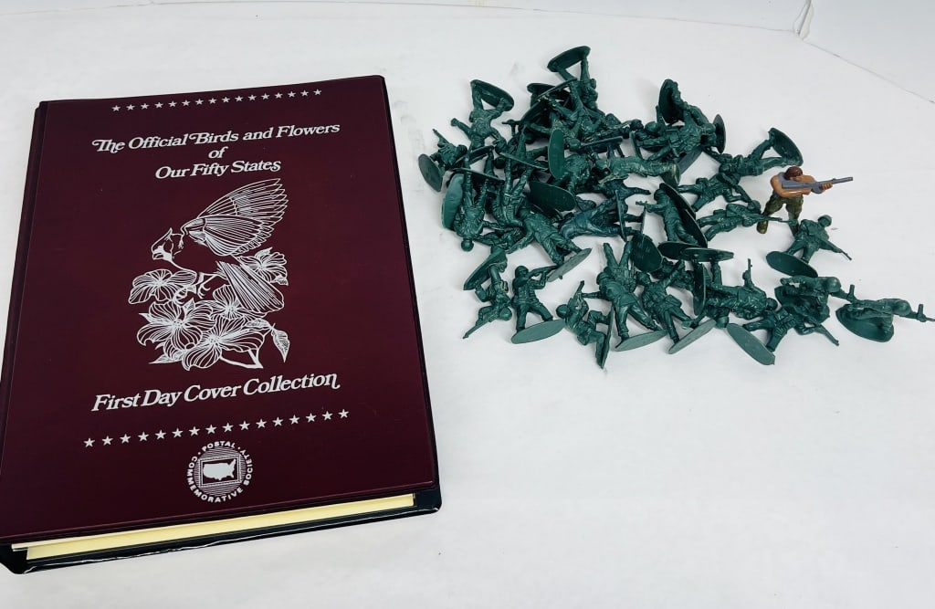 POSTAL COMMEMORATIVE SOCIETY ALBUM AND SOLDIERS, 1982: Maroon faux-leather binder housing a collection of Postal Commemorative Society First Day Covers featuring state birds and flowers from 1982. Accompanied by an assortment of molded green plastic toy s