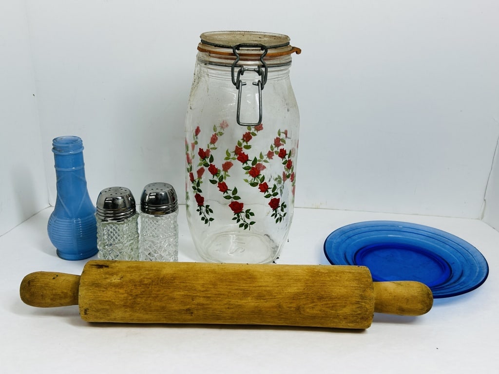 ASSORTED VINTAGE GLASS AND WOOD KITCHENALIA: An assortment of vintage kitchenware featuring a clear glass storage canister with a rose pattern attributed to Arc France and a turned wooden rolling pin. The collection also includes a cobalt blue g