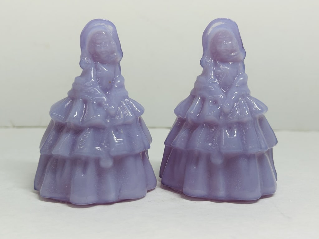 BOYD PURPLE SLAG GLASS LOUISE FIGURINES, 1983-1988: A pair of Louise pattern colonial lady figurines produced by Boyd's Crystal Art Glass in lavender slag glass. Both examples bear the embossed B in a diamond mark with one line below, dating them to th