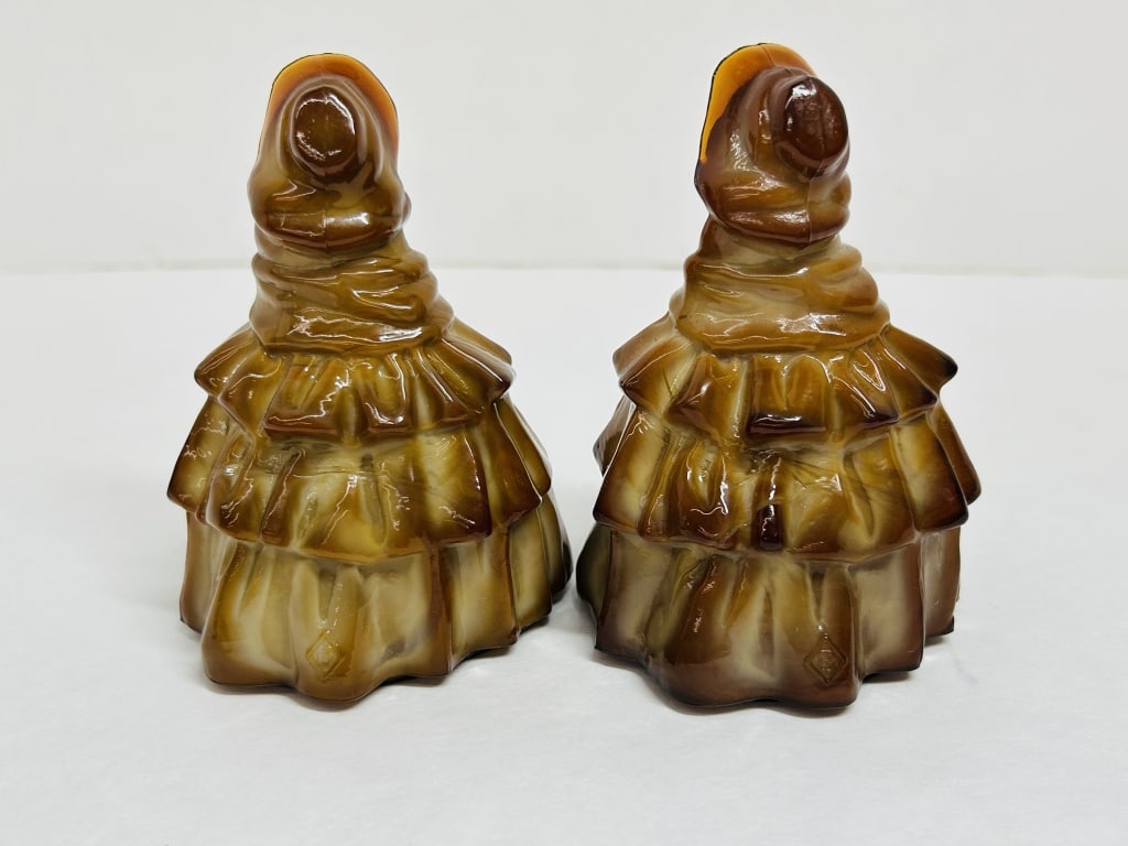 BOYD SLAG GLASS LOUISE FIGURINES, 1990-1994: A pair of Louise colonial lady figurines produced by Boyd's Crystal Art Glass. Rendered in caramel slag glass, each piece features a tiered ruffled skirt and bears the embossed B in diamond maker's ma